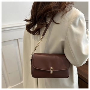 Détail d'un sac à bandoulière en cuir PU marron avec fermoir doré et bandoulière chaîne