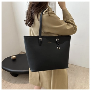 Detail shot of the large black tote bag featuring golden metal buckles and logo texture