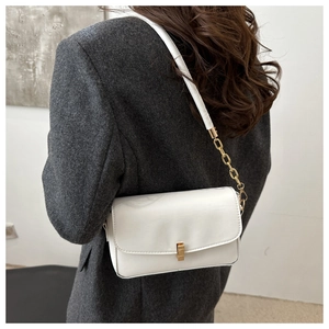 Gros plan du sac à bandoulière blanc brillant avec boucle dorée et bandoulière chaîne