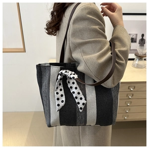 Close-up of vertical striped tote bag with brown leather straps and polka dot scarf detail