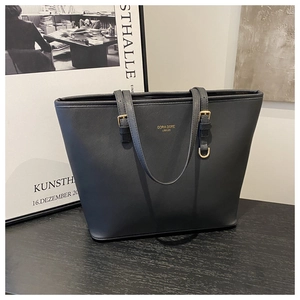Close-up of black Saffiano leather tote bag featuring gold brand logo and metal hardware