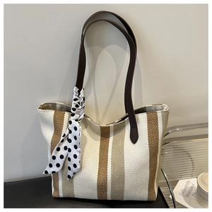 Detail of striped canvas tote bag with brown leather handles and a polka dot silk scarf