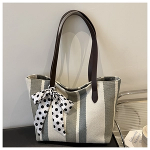 Detailed macro view of striped canvas tote bag texture with brown leather handles