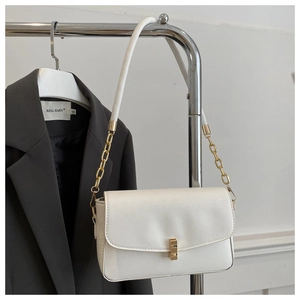 Détail d'un sac à bandoulière en cuir blanc avec fermoir doré et bandoulière chaîne