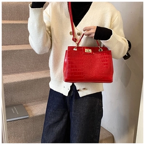 Detail of red crocodile texture handbag with golden metal lock and shoulder strap