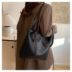 Detail view of large black leather tote bag with gold ring and decorative cord detail
