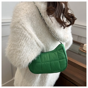 Modella indossa una borsa a spalla trapuntata verde con tracolla a catena d'argento