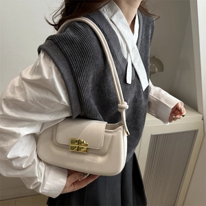 Cream beige faux leather shoulder bag with a gold square clasp on a female model