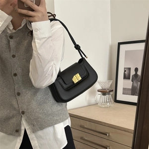 Minimalist black leather underarm bag with gold geometric buckle and knotted shoulder strap