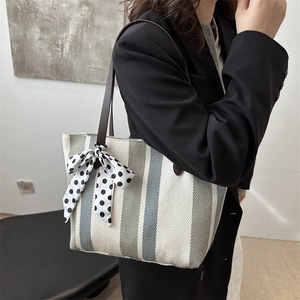 Vertical striped tote bag with polka dot bow accent shown on a female model shoulder