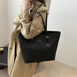 Classic black leather tote bag with gold logo shown on model for elegant daily use