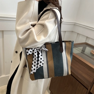 Women's vertical striped canvas tote bag with bow detail and brown leather handles