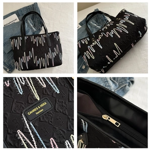 Détails d'un sac cabas noir matelassé avec broderie arc-en-ciel et plaque logo