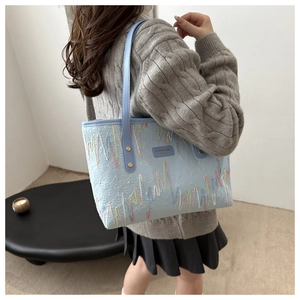 Détail du sac cabas bleu clair avec broderie ondulée et rivets métalliques dorés