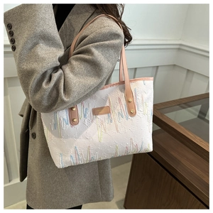 Détail d'un sac cabas blanc avec broderie verticale colorée et anses en cuir rose