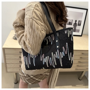 Gros plan d'un grand sac cabas noir avec motifs ondulés brodés colorés