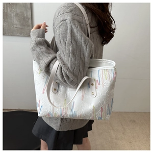 Détail du cabas blanc avec broderies zigzag colorées et textures de cuir embossées