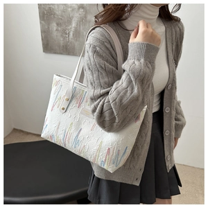 Détail du sac cabas blanc matelassé avec broderie ondulée et motifs embossés