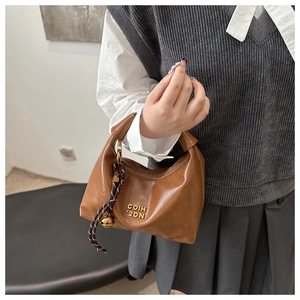 Detail view of brown vintage dumpling bag with glossy texture and gold letter logo