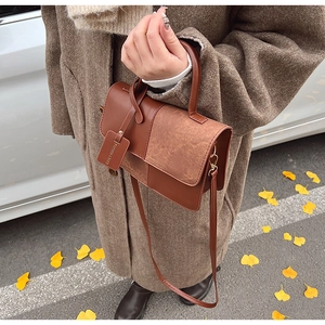 Detail of vintage brown leather handbag with fashion tag against autumn leaves