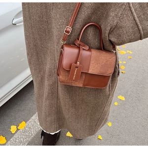 Chic brown patchwork crossbody bag styled in a scenic autumn setting with yellow leaves