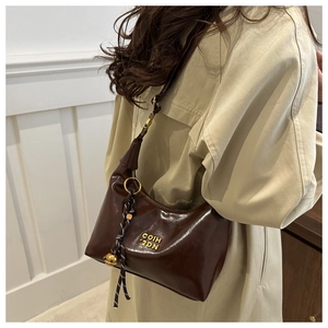 Detail of dark brown glossy crescent bag with gold logo and woven zipper charm