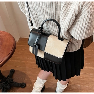 Detail of a chic square color-block crossbody bag with a fashion logo tag on a model