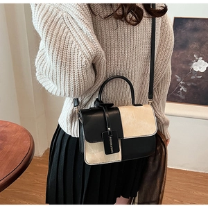 Detail shot of a minimalist black and beige contrast crossbody bag worn by a model