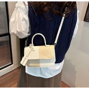 Detail view of contrast color leather handbag with fashion tag and detachable strap