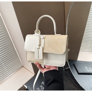 Detail view of contrast color square bag with khaki suede stitching and fashion tag