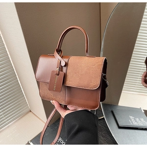 Detail of brown PU and suede patchwork handbag with adjustable strap and fashion tag