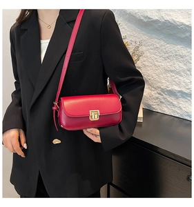 Détail d'un sac à bandoulière rectangulaire rouge foncé avec fermoir doré et sangle