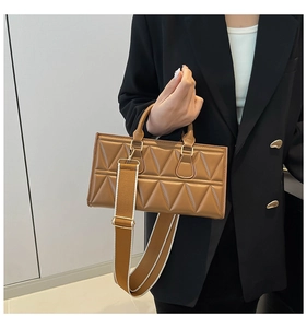 Detail of caramel brown crossbody bag featuring triangle quilting and wide strap