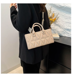 Detailed view of cream quilted square handbag with adjustable wide strap and top handles
