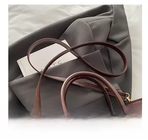 Detail of dark brown leather handbag with adjustable shoulder strap and round handle