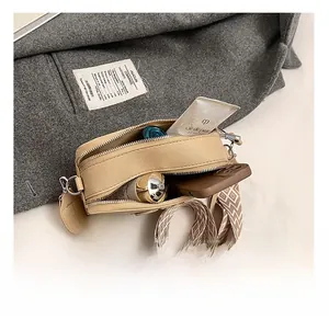 Detail view of beige crossbody bag interior with dual zippers and wide geometric strap