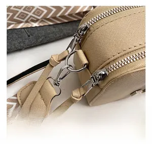 Detail of silver hardware and beige crossgrain leather on a shoulder bag with woven strap