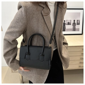 Chic black matte leather crossbody bag shown on model wearing a brown herringbone blazer