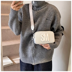 Detail of white leather camera bag with SM logo and geometric wide shoulder strap