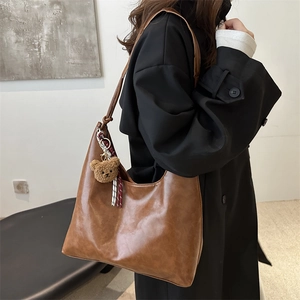 Retro brown faux leather tote bag with plush bear charm and tassel detail on model
