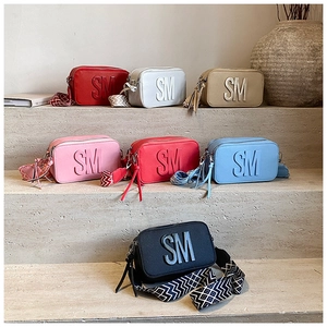 Detail of colorful crossbody bags featuring SM logo and geometric pattern wide straps