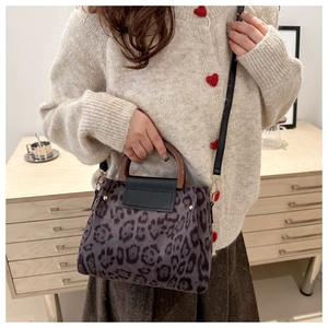 Dettaglio borsa leopardata con manico in legno e finiture dorate su maglione lavorato