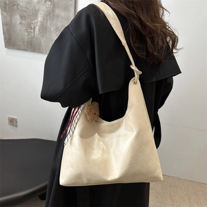 Minimalist off-white leather hobo tote bag with a plush bear pendant and knot detail