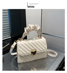 Detail of off-white ruched handbag with gold heart buckle and quilted texture