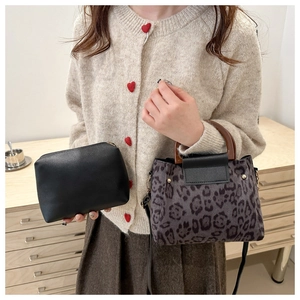 Detail of leopard print handbag with round wooden handle and a black zipper pouch