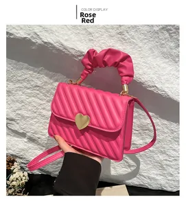 Close-up of rose red quilted handbag with golden heart buckle and scrunchie handle