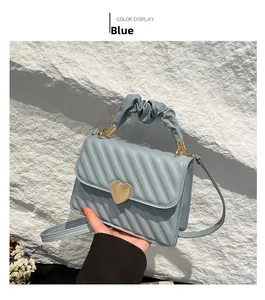 Detail of blue quilted handbag with golden heart clasp and stylish ruched handle