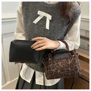 Detail view of leopard print handbag with wooden round handle and sleek black clutch bag