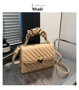 Detail of khaki quilted crossbody bag with golden heart clasp and pleated handle