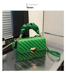 Detail of green quilted handbag featuring heart-shaped gold lock and pleated cloud handle